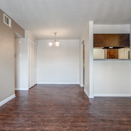 Spacious and well lit living room with wood flooring, large windows and open access to the kitchen